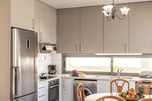 Eine moderne Küche mit Edelstahlgeräten, einem eingebauten Ofen, einem Geschirrspüler und einem großen Fenster für natürliches Licht.