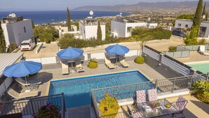 A rooftop pool with blue umbrellas, lounge chairs, and a view of the sea and mountains. - Lenias Sea View in Neo Chorio (Neo Chorio)