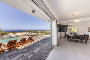 Ein modernes Hotelzimmer mit Balkon mit Blick auf einen Pool und das Meer.