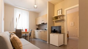 Eine moderne Wohnung mit Wohnzimmer, Essbereich, Küche und einem kleinen Fernseher auf einem Schrank.