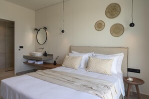 Ein modernes Schlafzimmer mit einem großen Bett, einem Nachttisch, einem runden Spiegel und einem an der Wand montierten Regal mit einem Waschbecken.