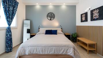A modern bedroom with a bed, bedside tables, a mirror, and artwork on the wall.