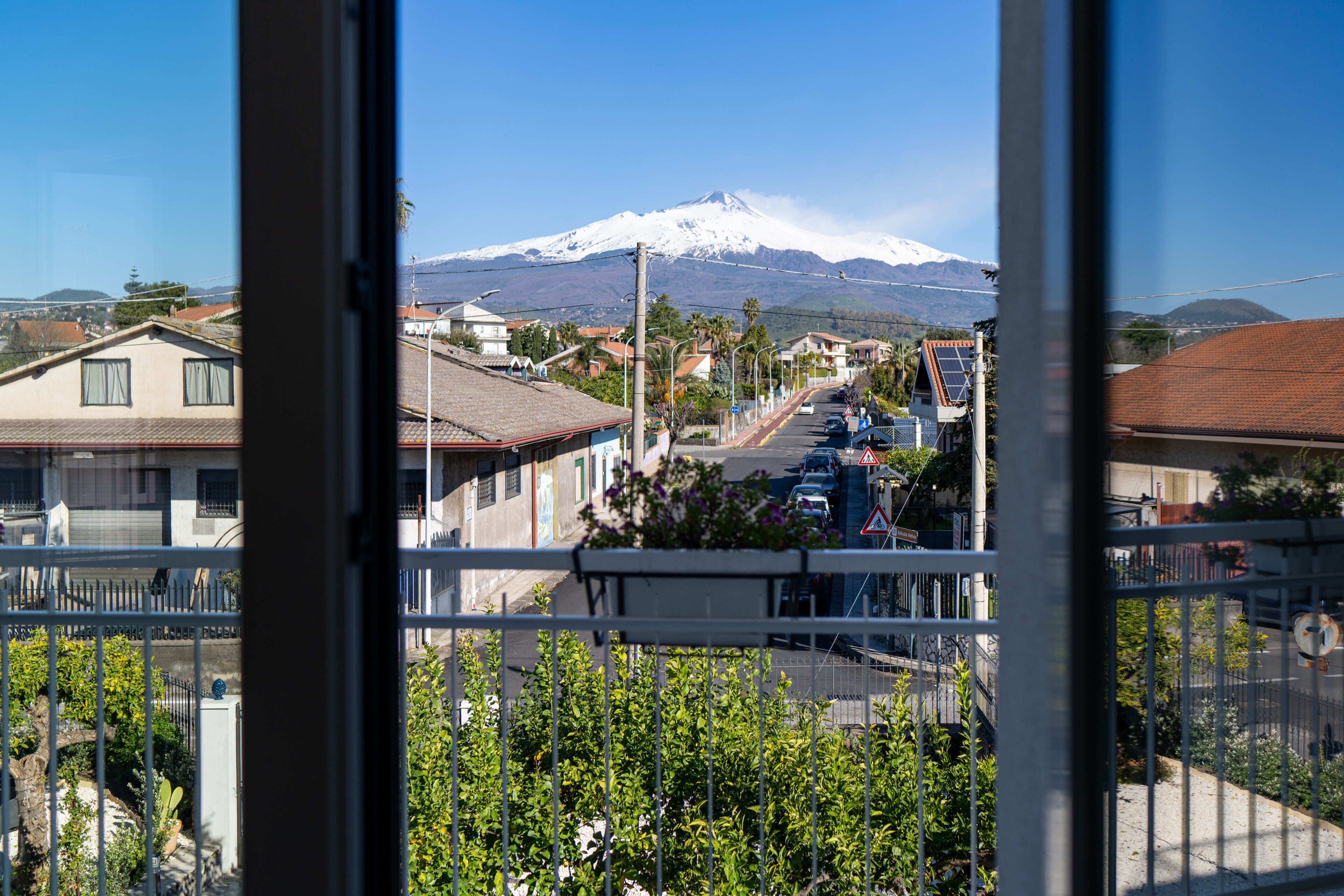 A residential street with houses, parked cars, and a mountain in the background.