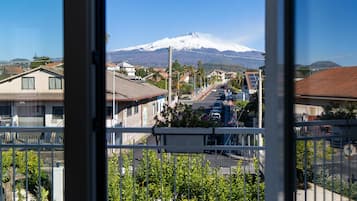 A residential street with houses, parked cars, and a mountain in the background.