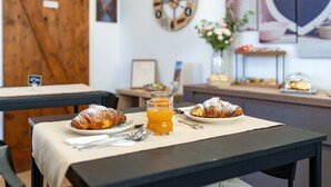 A breakfast setting with croissants, orange juice, and a clock on the wall.