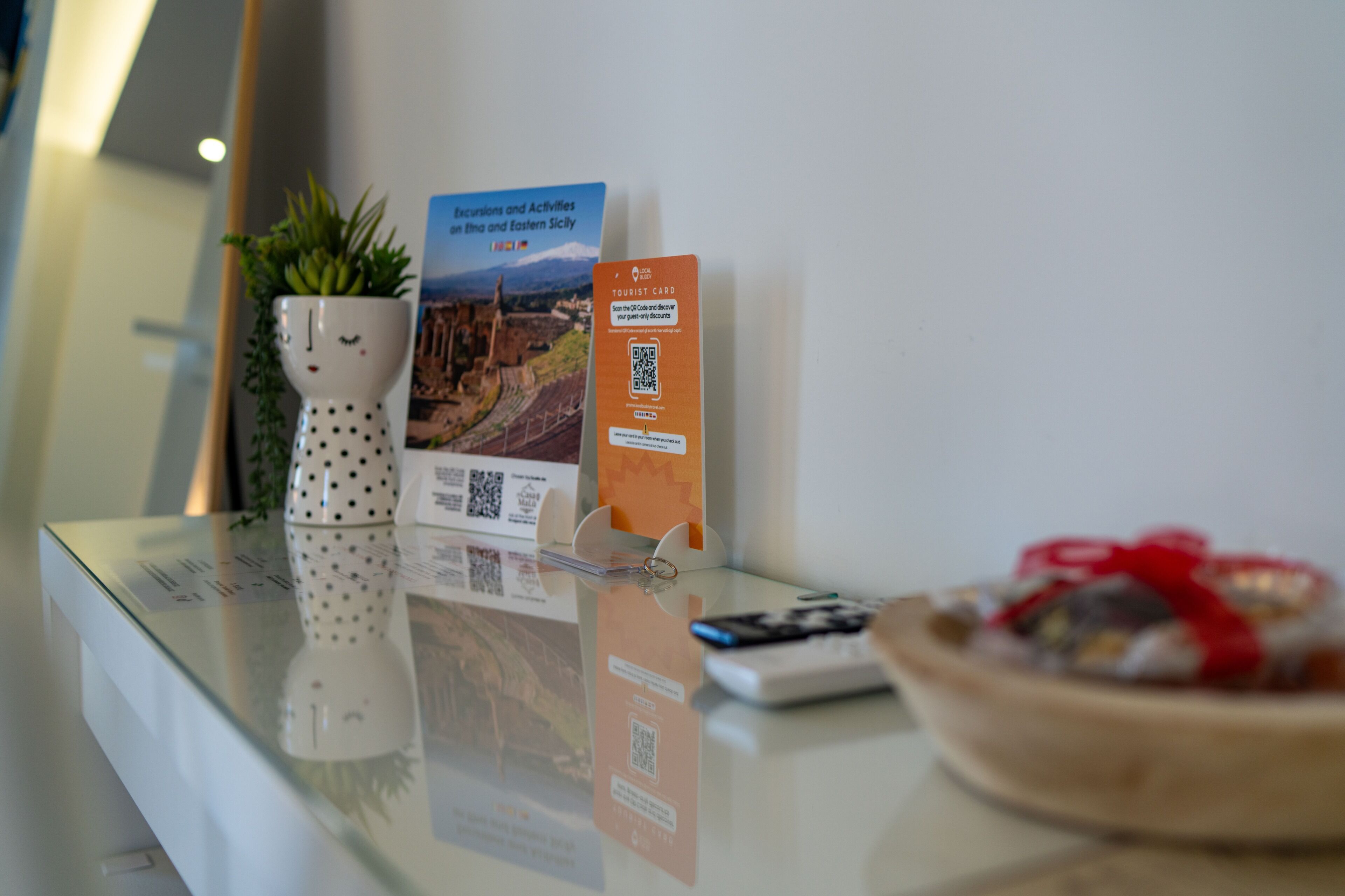 Un comptoir d’accueil agrémenté d’une plante, d’une carte touristique et d’une télécommande.