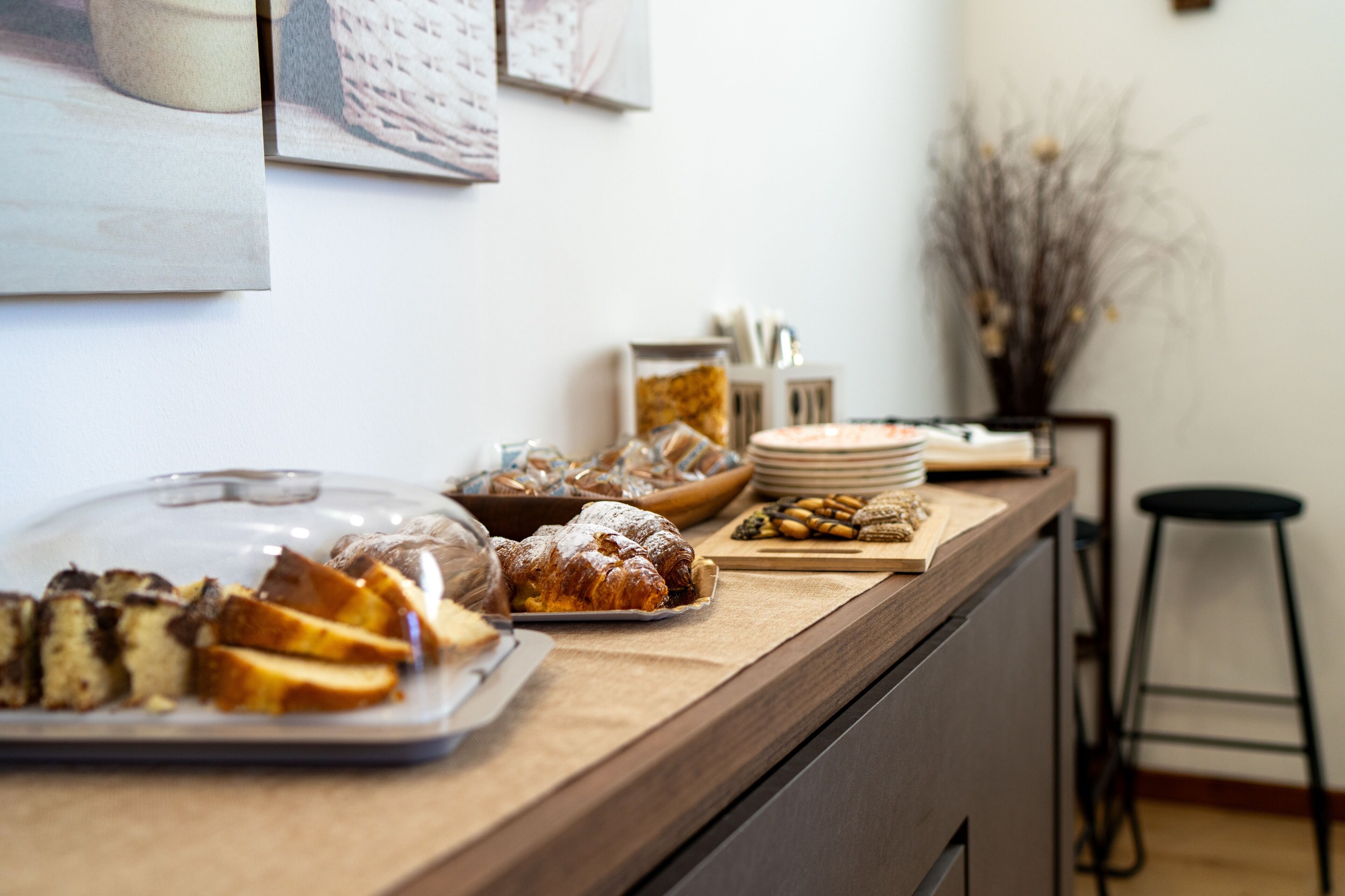 Un banco buffet con diversi cibi, tra cui pasticcini e pane, e un angolo per il caffè.