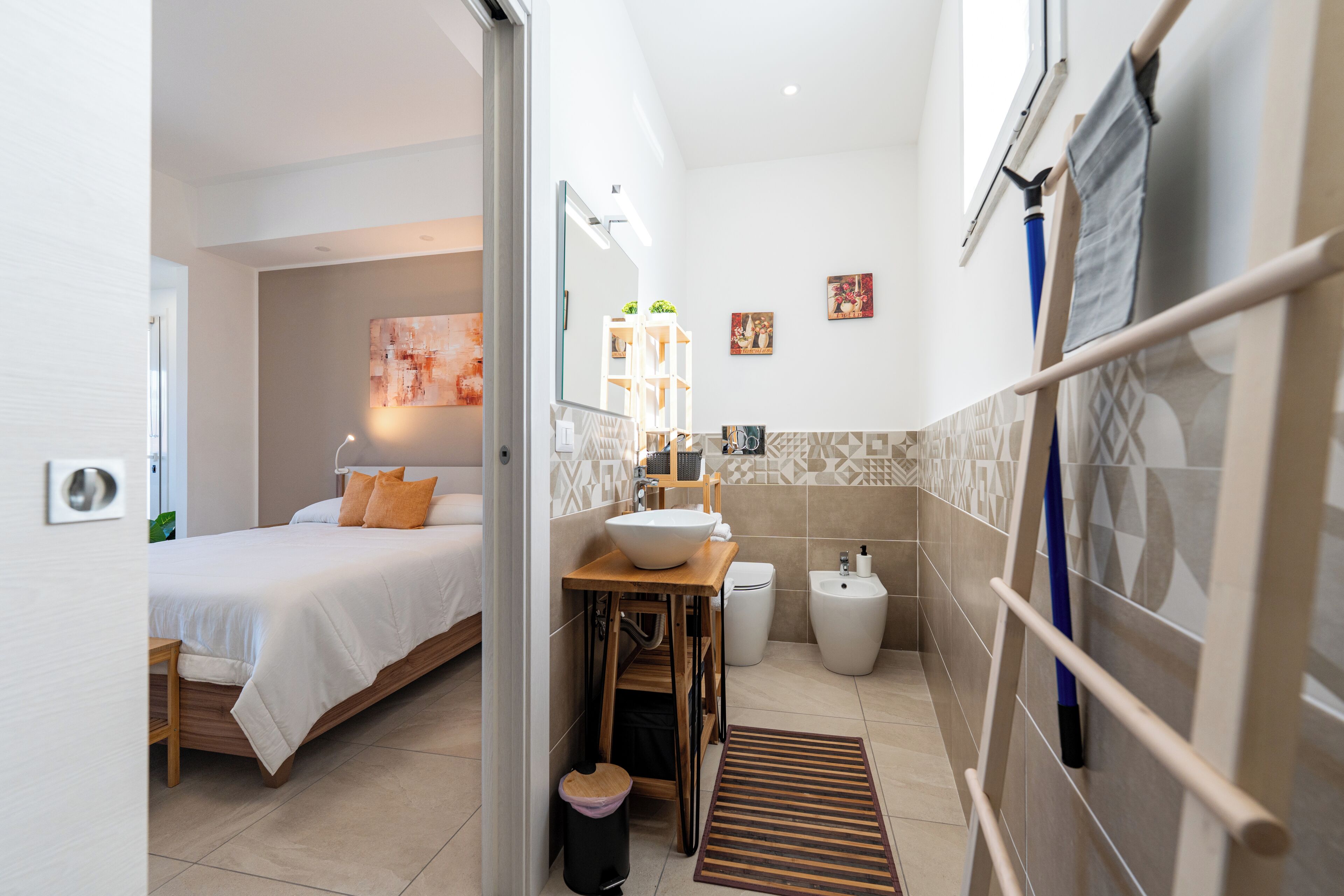 A hotel room with a bed, a bathroom with a sink and toilet, and a small kitchenette.