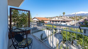 A balcony with a table and chairs, a view of houses and a mountain in the distance.