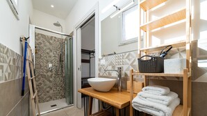 A modern bathroom with a shower, a sink, and a towel rack.