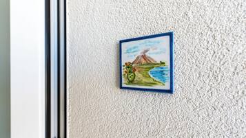 A framed picture of a volcano and cactus on a textured wall.