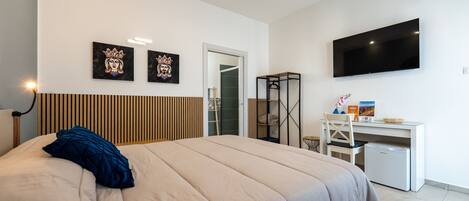 Una habitación de hotel moderna con una cama grande, un escritorio, un televisor de pantalla plana y obras de arte en la pared.