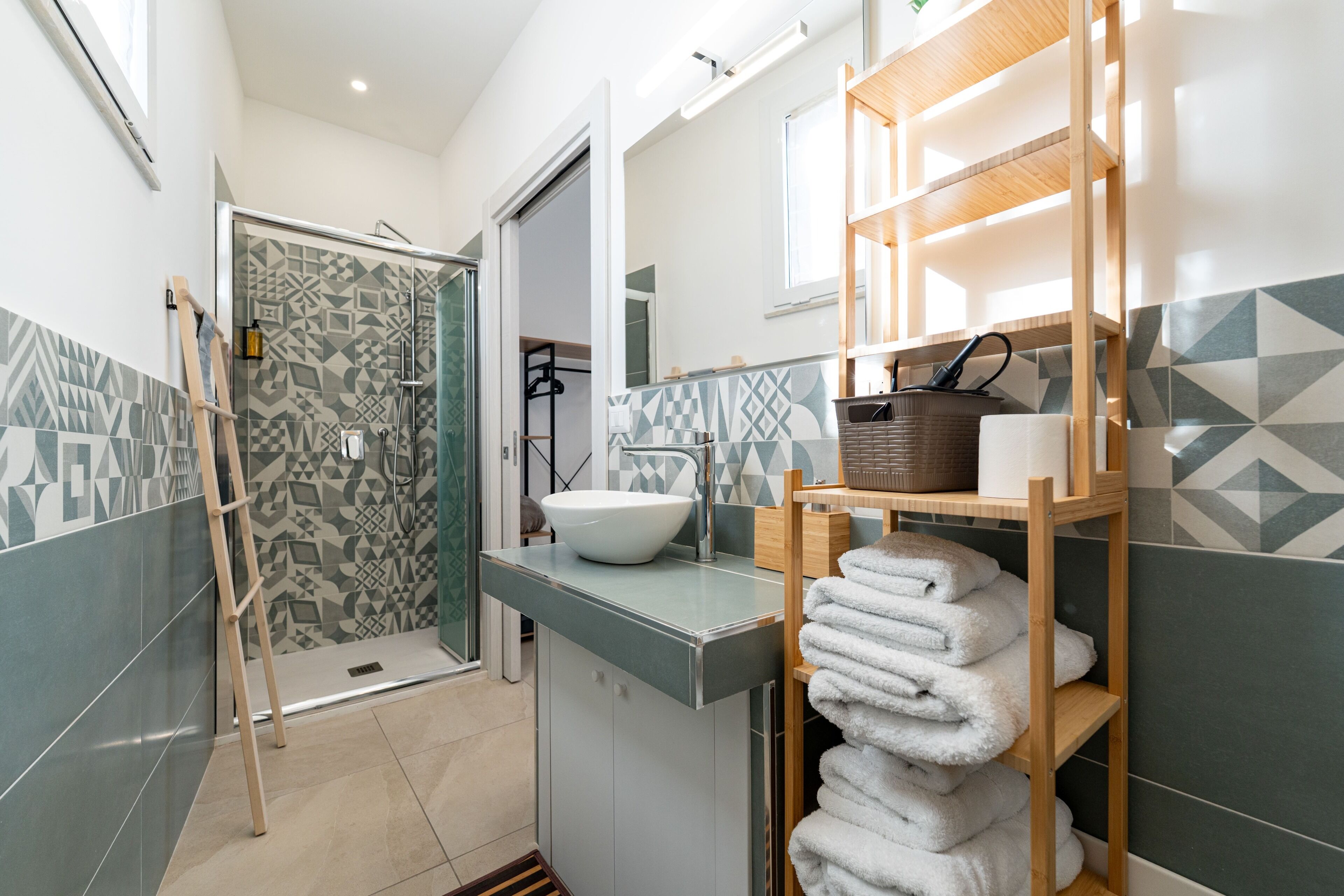 Un baño moderno con ducha, lavamanos y un perchero para toallas.