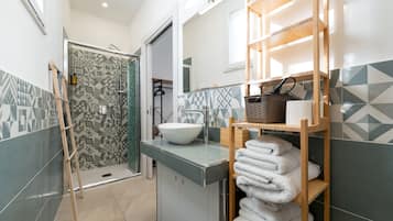Un baño moderno con ducha, lavamanos y un perchero para toallas.