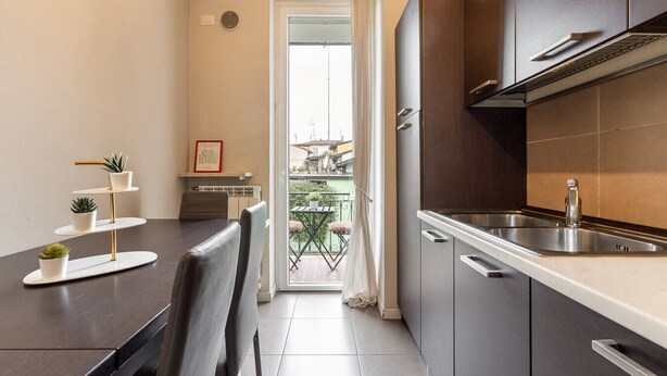 Una cucina compatta con lavello, mobiletti e zona pranzo con tavolo e sedie.