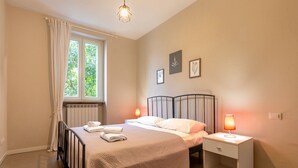 Una camera da letto con un letto, due comodini con lampade, una finestra con tende e quadri appesi al muro.