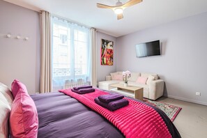 A bedroom with a bed, a sofa, a TV, and a window with curtains. - Maison Opaline, 5 bedrooms, view of the Basilica and garden (Reims)