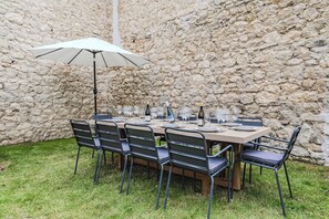 A stone wall, a table with chairs, and an umbrella. - Maison Opaline, 5 bedrooms, view of the Basilica and garden (Reims)