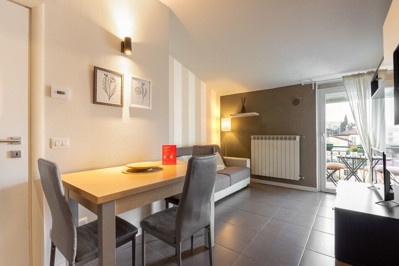 A modern living room with a dining area, a sofa, a coffee table, and a radiator.