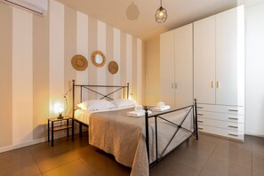 Un dormitorio con cama, lámparas de noche, un armario y espejos decorativos en la pared.