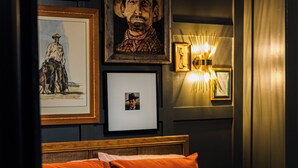 A bedroom with a bed, framed pictures, and a wall-mounted light fixture. - The Silo On 16 (Graham)