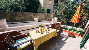 A patio with a table set for two, surrounded by wooden chairs, a yellow tablecloth, and an orange umbrella. - Standard Studio near the beach (Agios Gordios)