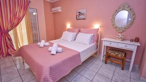 A bedroom with a bed, a desk, a chair, a mirror, and a window with curtains. - Standard Studio near the beach (Agios Gordios)