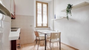 A kitchen with a window, white cabinets, a white countertop, and a dining table with chairs. - The Light Flat Bonghi is a bright and welcoming apartment just steps from Bocconi University, ideal for seating up to 6 people.It has two bedrooms and a living room with a sofa bed, perfect for relaxing moments after a day in the city.The rooms are well- (Milan)