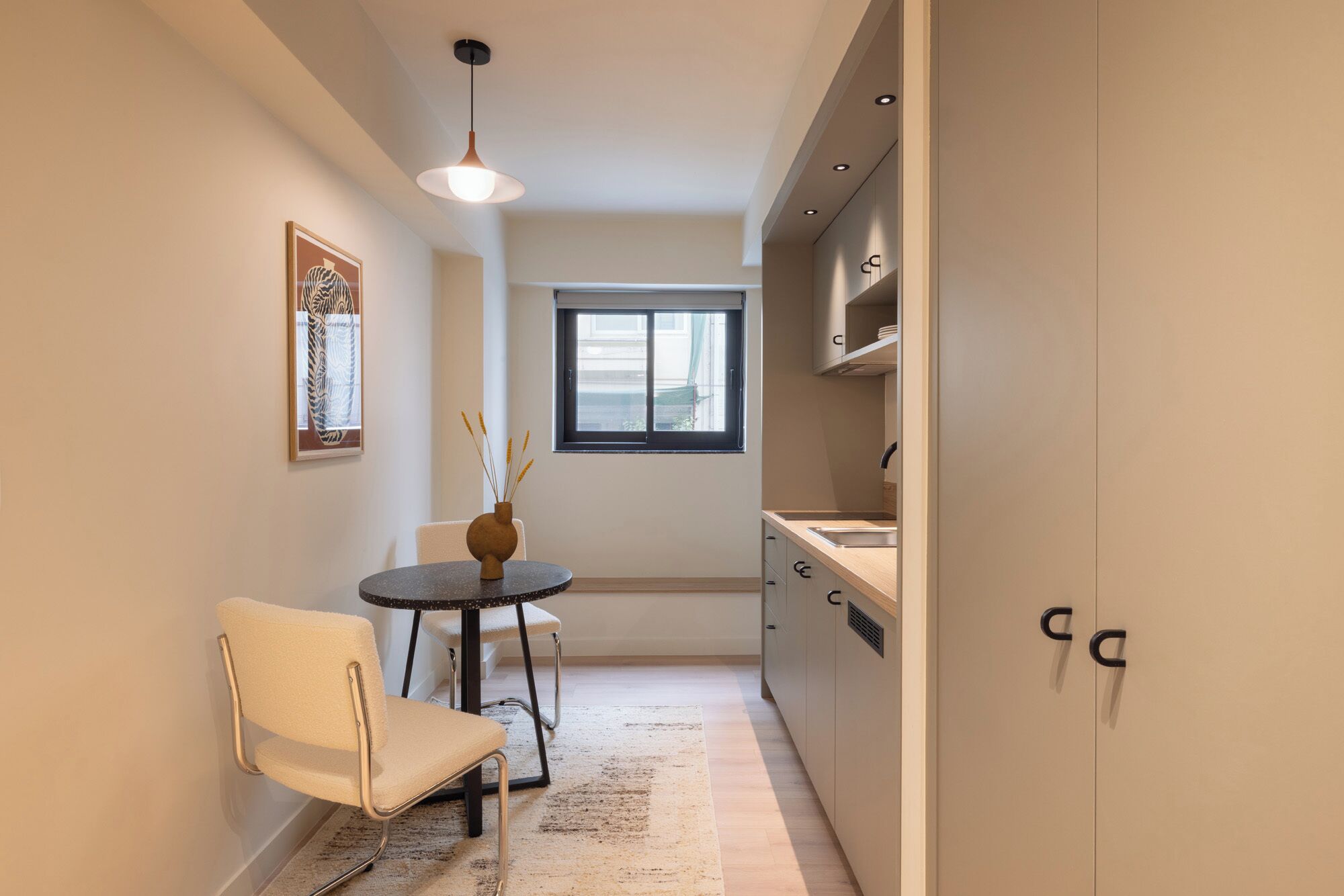 A compact kitchen with a dining area, a window, and a pendant light.