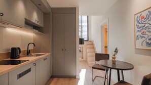 A modern kitchen with a built-in oven, a sink, and a dining area with a table and chairs. - Leon II by Zoia Living (Piraeus)