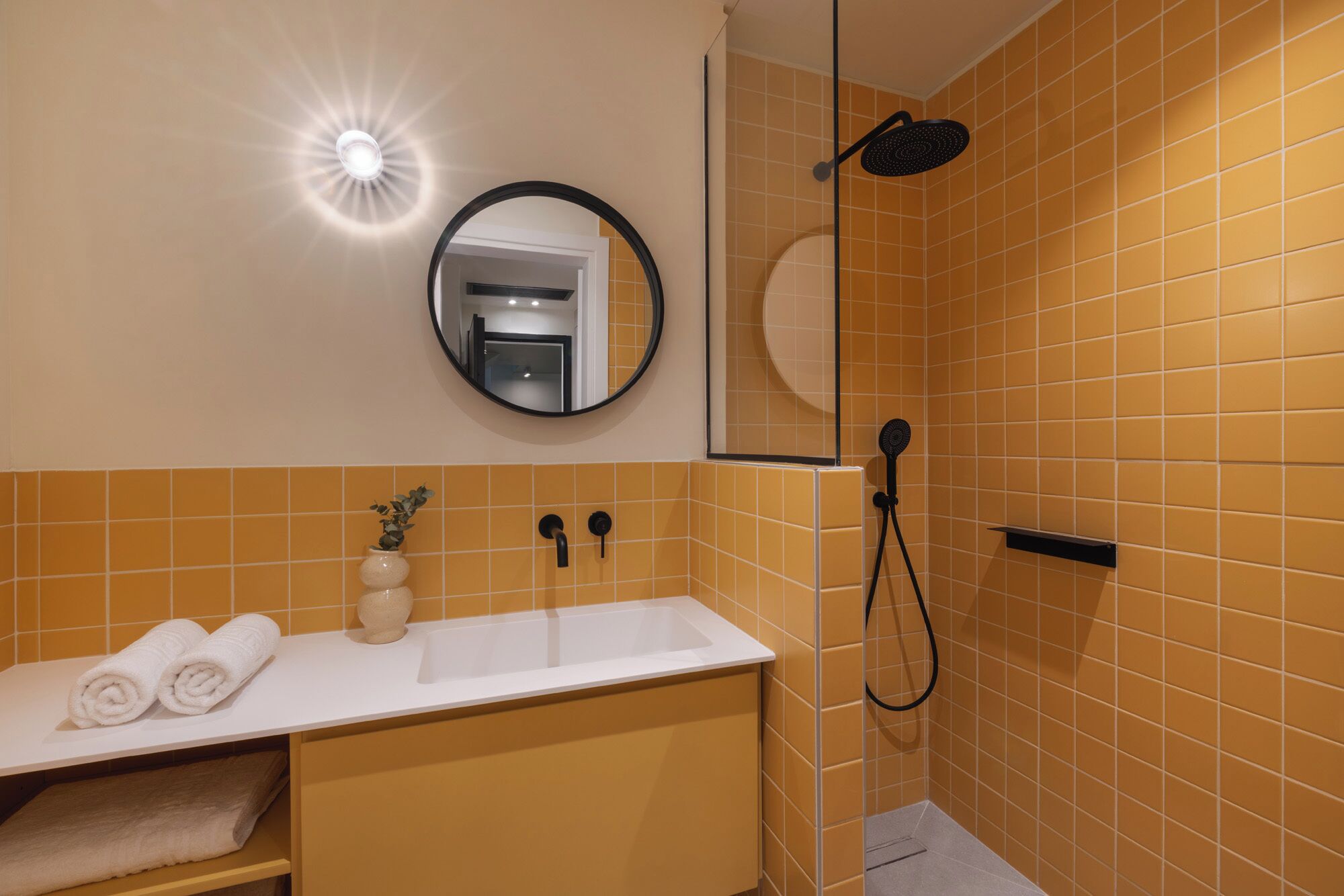 A bathroom with a white sink, a mirror, a shower, and a towel rack.