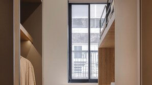 Una habitación compacta con armario empotrado, un pequeño rincón de descanso con mesa, y ventana con vistas al exterior.