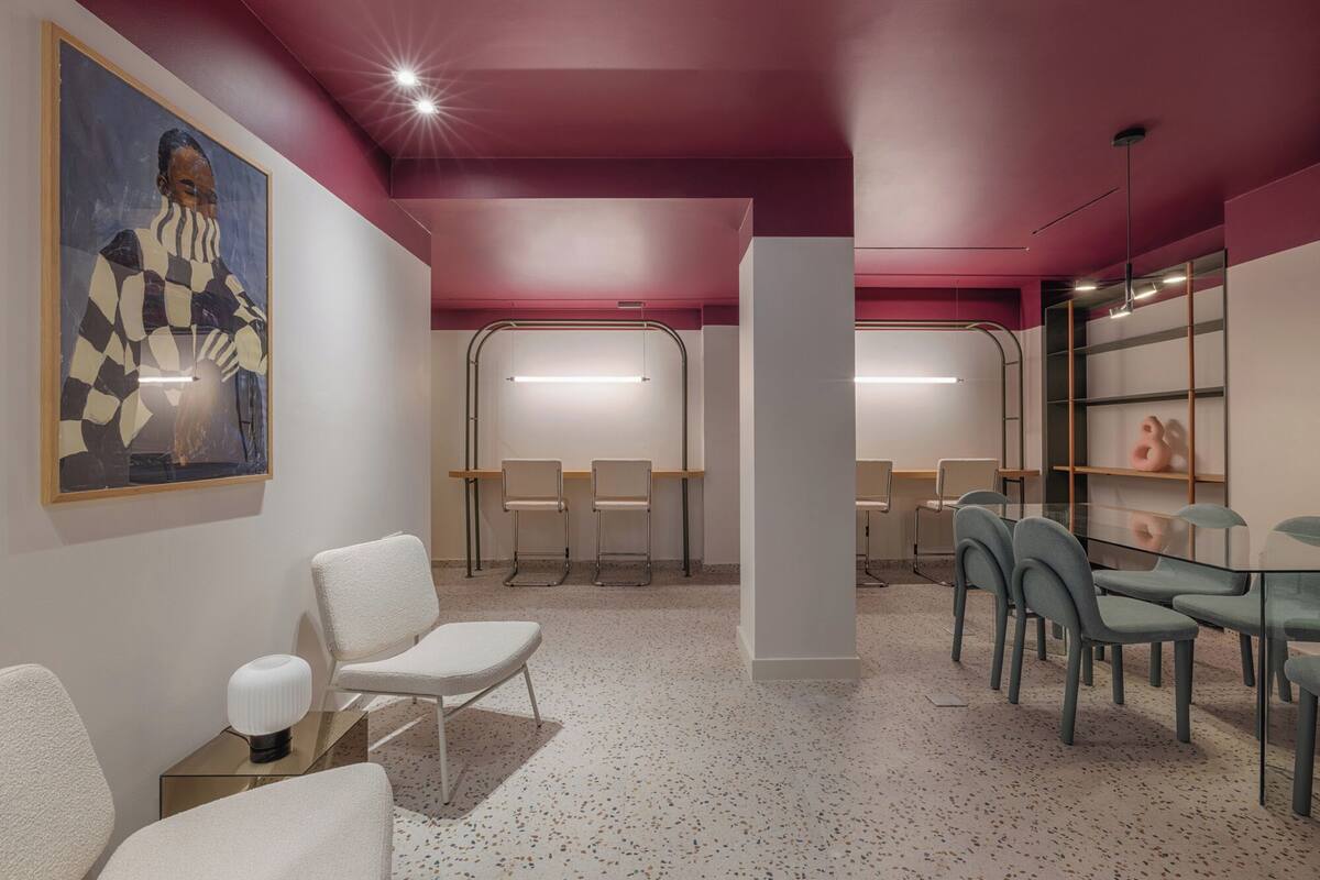 A modern waiting area with chairs, a glass table, and a painting on the wall.
