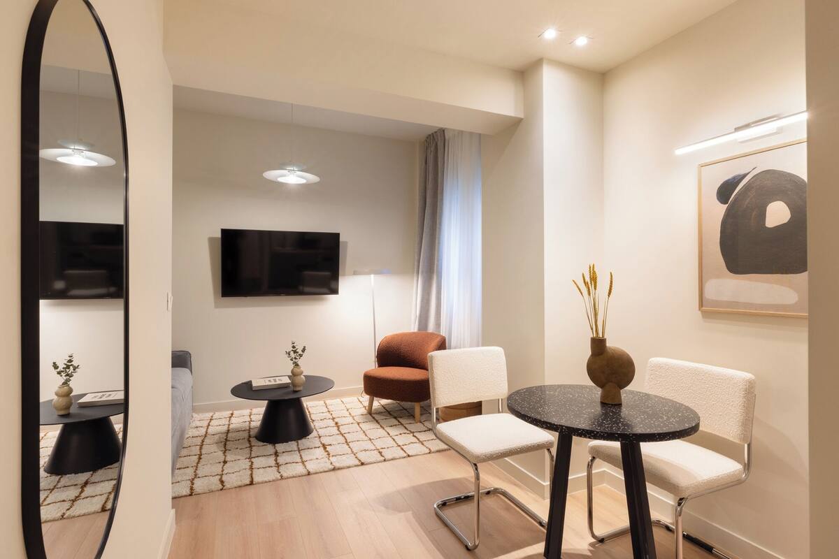 A modern living room with a sofa, two chairs, a coffee table, a TV, and a painting on the wall.