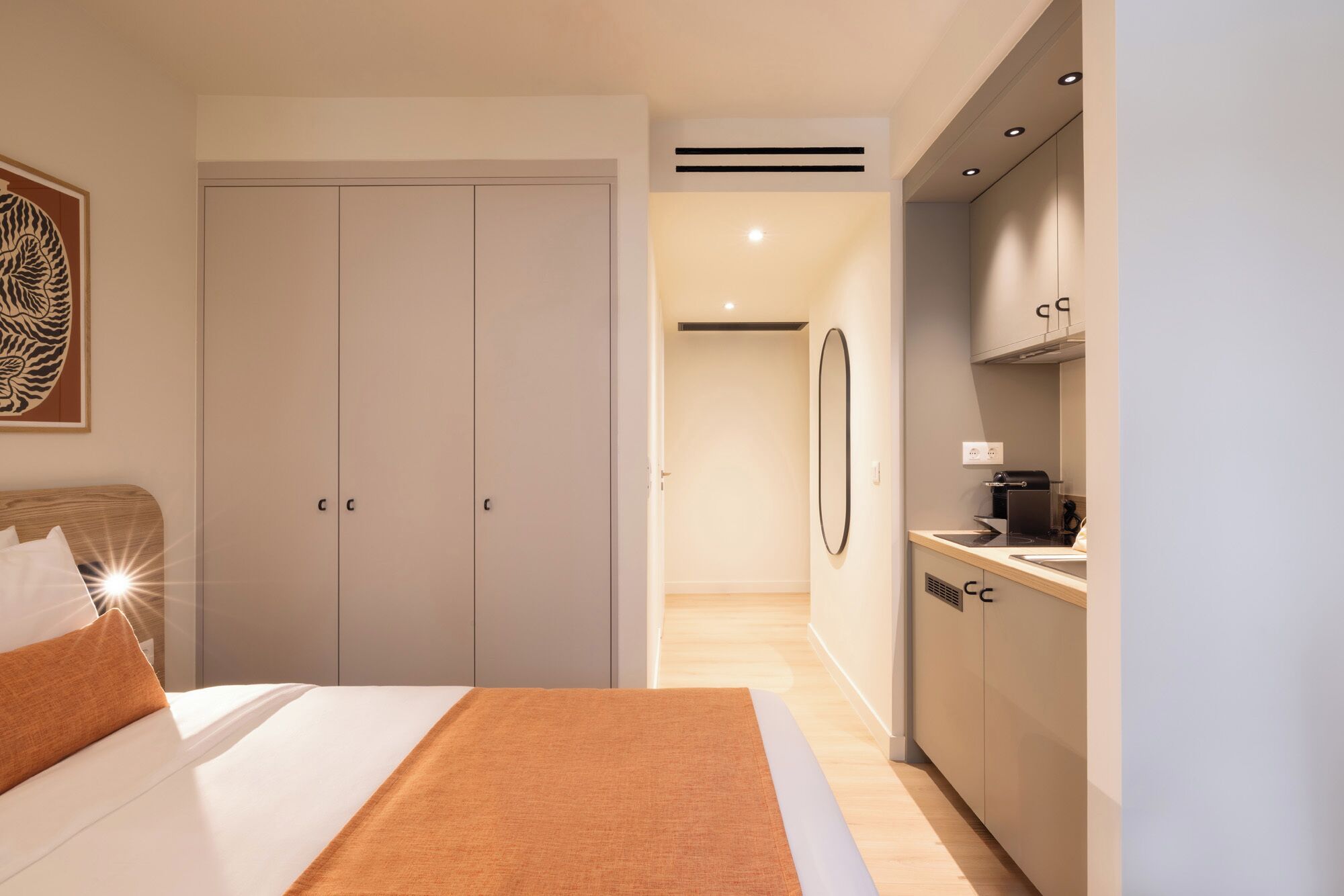 Una habitación de hotel moderna con cama, armario, kitchenette y baño.