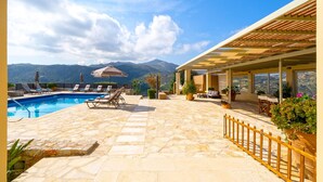 A pool area with lounge chairs, a pergola, and a view of mountains. - Sea Soul Luxury Villa with private swimming pool (Crete)