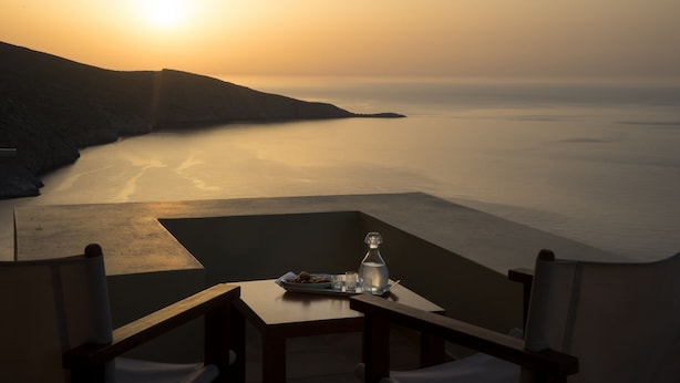 A table with a bottle and glasses, overlooking a calm sea and a hilly landscape during sunset. - Sea Soul Luxury Villa with private swimming pool (Crete)