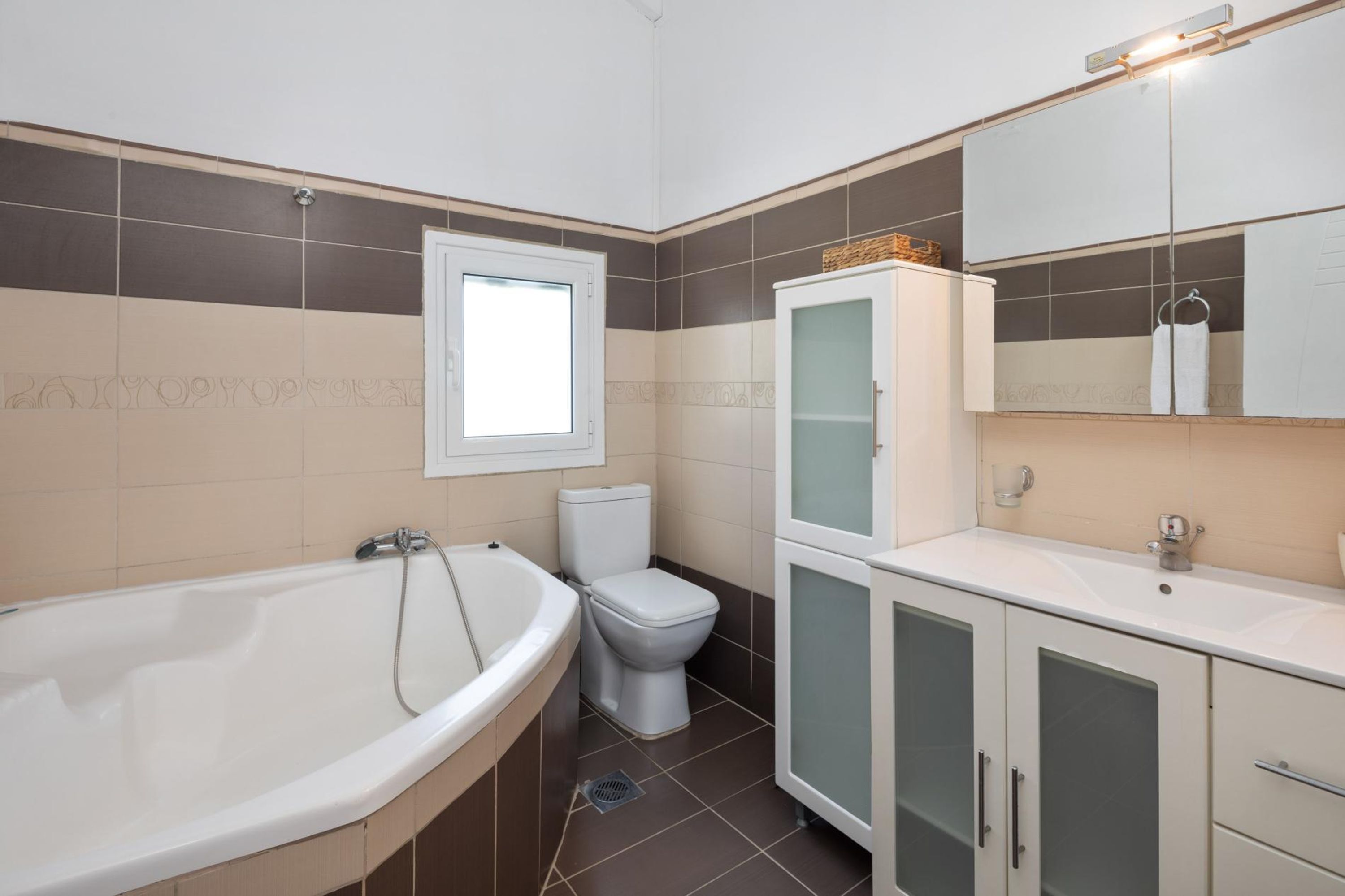Un baño con bañera, inodoro y tocador con armarios.