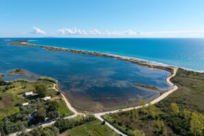 An aerial view of a coastal area with a clear road leading to a beach, surrounded by greenery and a large body of water. - Villa Anastasis in Crete (Crete)