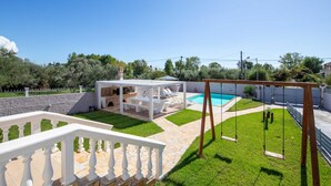 A backyard with a swimming pool, a wooden swing set, and a covered seating area. - Villa Anastasis in Crete (Crete)
