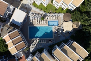 An aerial view of a hotel with a central swimming pool surrounded by sun loungers and a smaller pool. - Dream House in Tragaki (Tragaki)