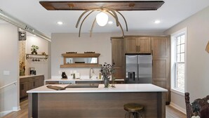 A modern kitchen with wooden cabinets, a central island, and a stainless steel refrigerator.
