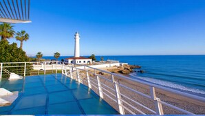 A beachside view with a white building, a lighthouse, and a clear blue sky. - Castillo Bajo in Torrox (Torrox)