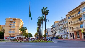 A street view with a prominent sign reading 'TORROX COSTA' and a flagpole with a flag. - Castillo Bajo in Torrox (Torrox)
