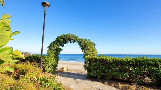 A pathway leading to a beach with a decorative archway and a street lamp. - Castillo Bajo in Torrox (Torrox)