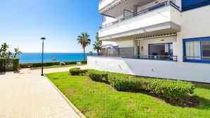 A modern building with a balcony, a paved walkway, and a view of the sea. - Castillo Bajo in Torrox (Torrox)