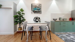 Een moderne keuken met een eettafel, stoelen, een potplant en een schilderij aan de muur.