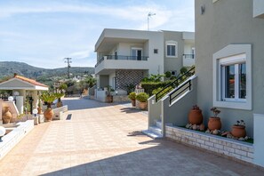 A two-story building with a balcony, potted plants, and a tiled patio area. - Villa Marie with private pool (Rethymno)