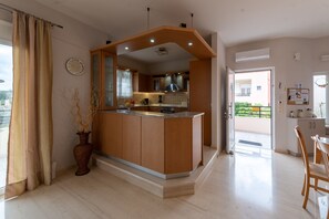 A modern kitchen with a central island, wooden cabinets, and a view to the outside. - Villa Marie with private pool (Rethymno)