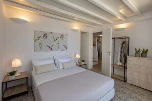Una camera da letto con un letto grande, comodini illuminati da lampade, un quadro appeso al muro, un armadio e una porta che dà su un'altra stanza.